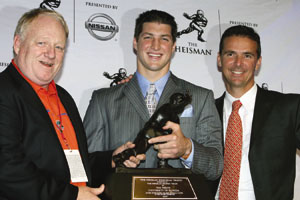 Tebow with his coaches and trophy.